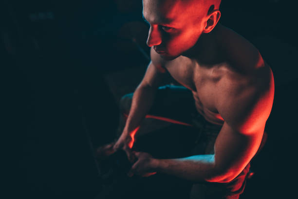 istock Shirtless man sitting in dark gym 1133559913