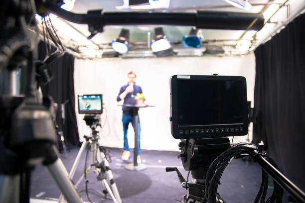 istock Journalist in a television studio is talking into a microphone, blurry film cameras 1133560216