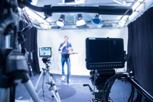 istock Journalist in a television studio is talking into a microphone, blurry film cameras 1133560218