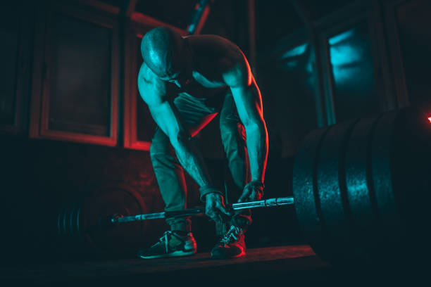 istock Fit man weightlifting in dark gym 1133561524
