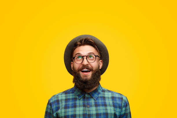 Excited man with beard looking up Amazed young hipster in shock looking up with surprise standing on bright yellow backdrop looking up stock pictures, royalty-free photos & images