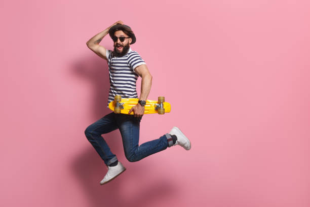 Excited hipster with skateboard jumping