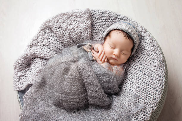 Sweet newborn baby sleeps in a basket. Beautiful newborn boy with bear toy. stock photo