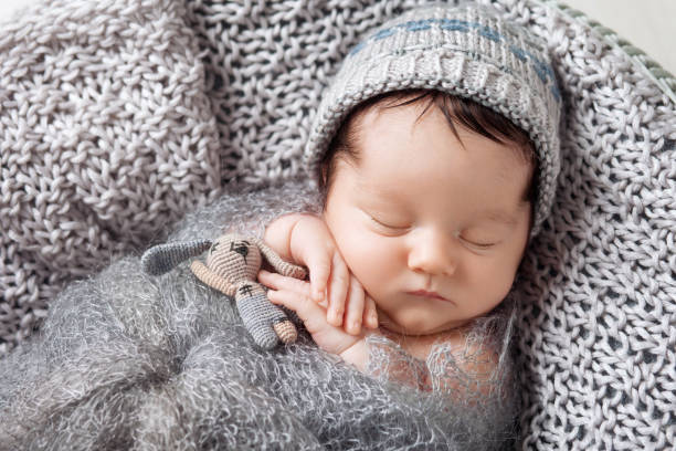 süßes neugeborenes schläft in einem korb. schöner neugeborener junge mit bärenspielzeug. - baby beauty beautiful the human body stock-fotos und bilder