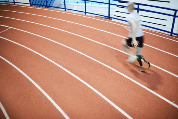 Fast motion Blurry runner with handicapped leg moving fast on one of race tracks at indoor stadium during competition paralympic games stock pictures, royalty-free photos & images