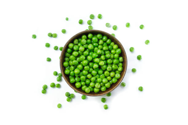 istock green peas on wooden bowl on white background. 1133566110