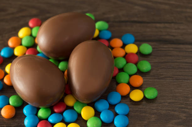 istock Easter. Chocolate eggs with multicolored candies lie on a wooden brown table. 1133566119