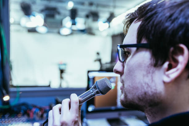 istock Studio recording: Young man speaks into a microphone, studio in the blurry background 1133566787