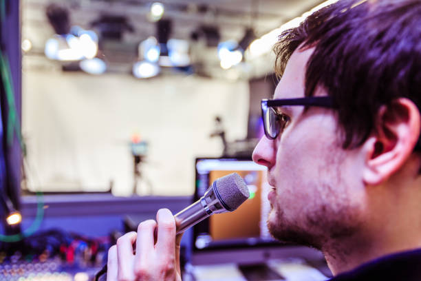 istock Studio recording: Young man speaks into a microphone, studio in the blurry background 1133566791