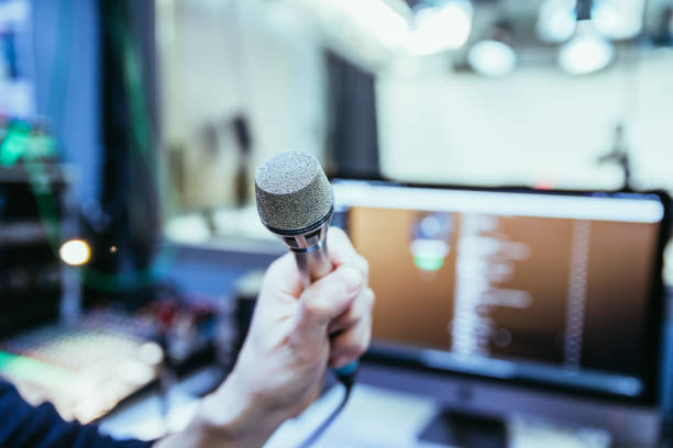 istock Studio recording: Young man speaks into a microphone, studio in the blurry background 1133566817