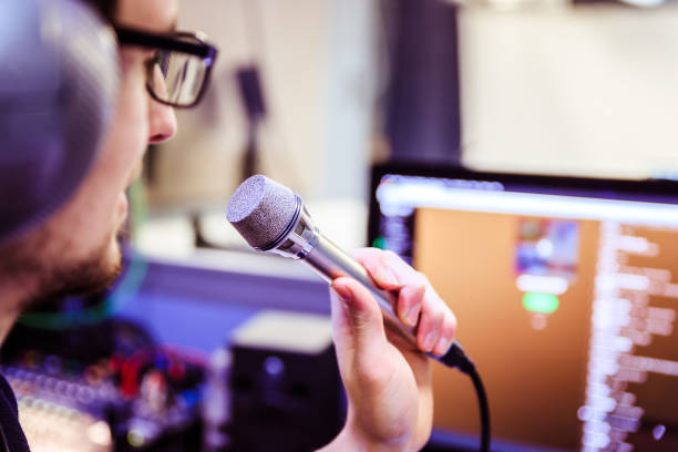 istock Studio recording: Young man with headphones speaks into a microphone, studio in the blurry background 1133566839