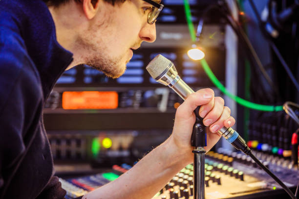 istock Studio recording: Young man speaks into a microphone, studio in the blurry background 1133566889