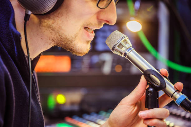 istock Studio recording: Young man with headphones speaks into a microphone, studio in the blurry background 1133566891