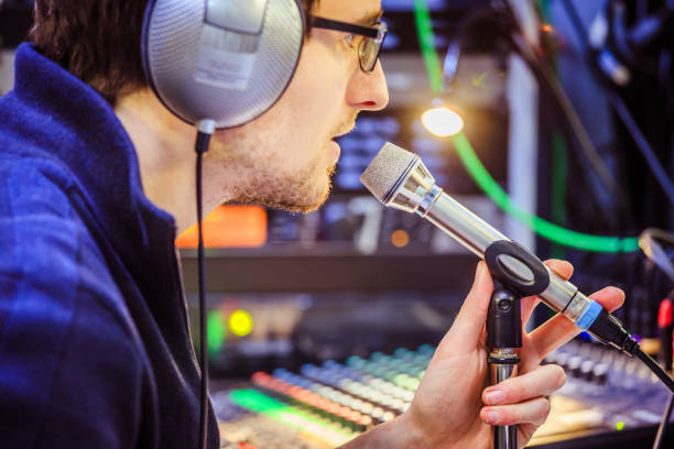 istock Studio recording: Young man with headphones speaks into a microphone, studio in the blurry background 1133566893