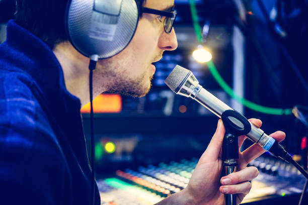 istock Studio recording: Young man with headphones speaks into a microphone, studio in the blurry background 1133566900
