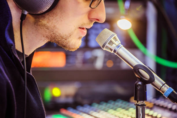 istock Studio recording: Young man with headphones speaks into a microphone, studio in the blurry background 1133566912