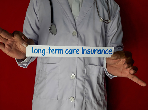 A doctor standing, Hold the long-term care insurance paper text on red background. Medical and healthcare concept.