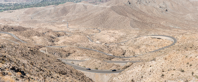 A winding desert mountain road in California with cars driving uphill