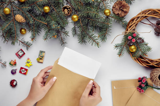 istock Christmas table with various items. Woman's hands putting a letter in an envelope. 1133576993