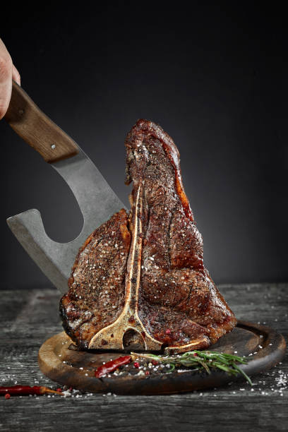 grilled t-bone steak with salt and pepper on cutting board on dark background - beef meat t bone steak steak imagens e fotografias de stock