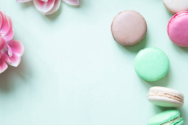 istock Colorful macaron or macaroon cakes and tulips on pastel green background with copy space. 1133578299