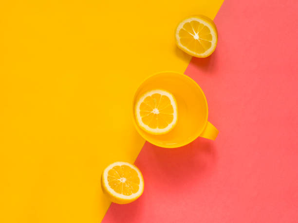 istock Creative fresh layout. Water with lemon in a yellow mug on a yellow and pink geometric background. Healthy drink, live water, lemonade. Biohacking minimalist concept. Flat lay 1133579590