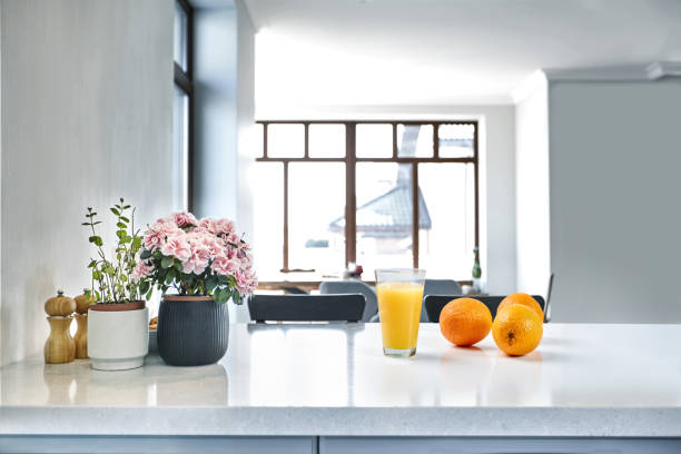 istock Appetizing sweet orange juice and one drinking glasses standing on a white table in the kitchen for a breakfast. 1133581753