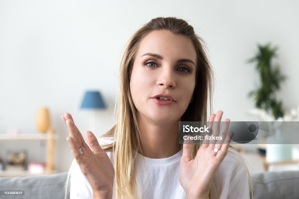 Head shot portrait talking woman, looking at camera, video call Head shot portrait friendly talking woman, looking at camera, making video call, attractive popular vlogger recording vlog or webinar for channel, explaining, sitting at home on cozy sofa Talking Stock Photo