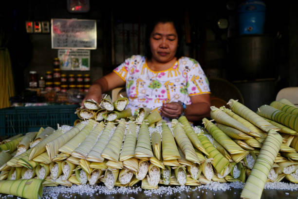 A food vendor wraps raw glutenous rice into palm leaves stock photo