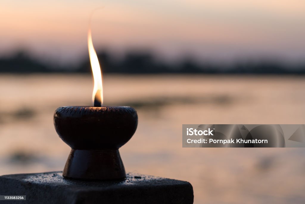 Candle light fire lamp nearby abstract background river during sunset or sunrise in countryside. Melting candlestick in evening twilight. Religion abstract concept. Mourning Stock Photo