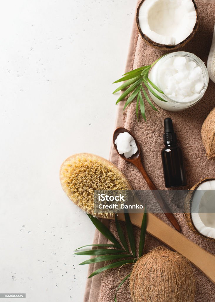 Dry massage brush with coconuts oil, health wellness concept with accessories on white background Dry massage brush with coconuts oil, health wellness concept with accessories on white background, copy space, top view, flat lay, vertical Coconut Stock Photo