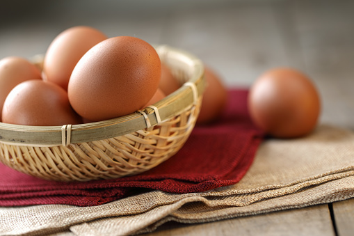 Fresh eggs stacked in a bamboo basket on wooden table