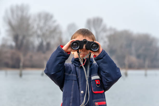 istock Little boy looking through binoculars on river bank 1133584879