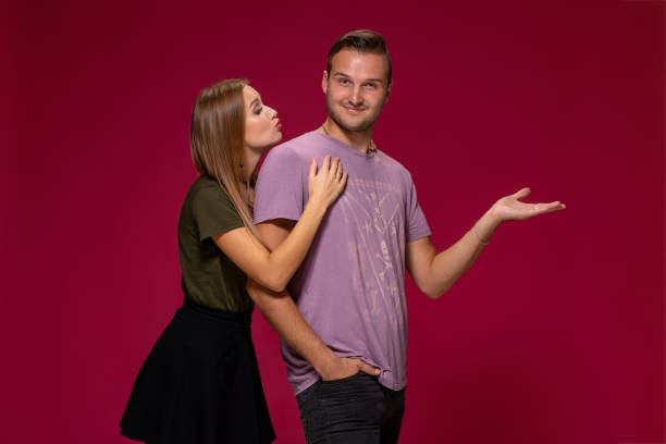 istock Young nice couple posing in the studio, express emotions and gestures, smiling, on a burgundy background 1133585340