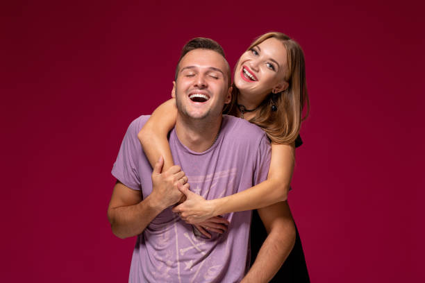 istock Young nice couple posing in the studio, express emotions and gestures, smiling, on a burgundy background 1133585958