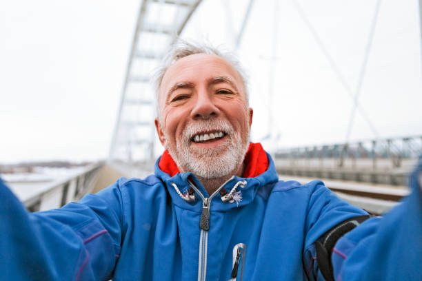 Senior man warming up for jogging on a city bridge taking selfie