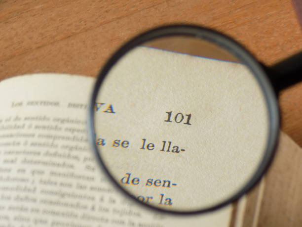 Magnifying Glass on page The composition shows a magnifying glass used in reading a page. documento stock pictures, royalty-free photos & images