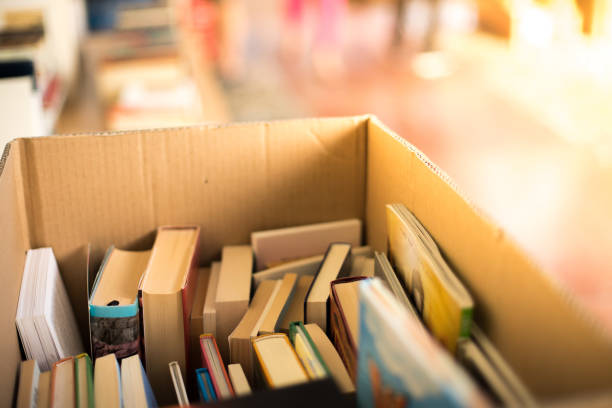 Stack of books, blurry background: Charity book flea market, outdoors. Text space.