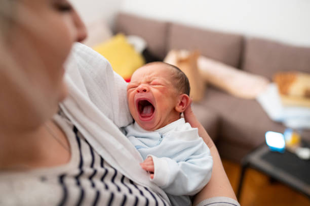 High angle view of unrecognizable mother holding newborn baby boy, baby crying with opened mouth