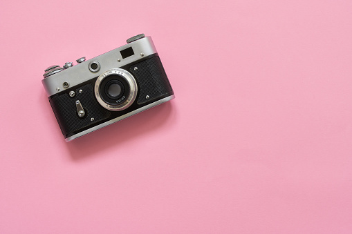 Flatlay vintage retro camera on pink background. Copy space, top view. Minimalistic concept.
