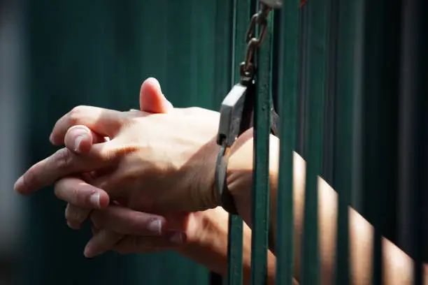 Photo of hand of prisoner in jail background.