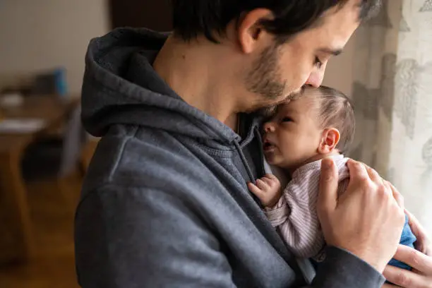 Photo of Proud father kissing newborn son