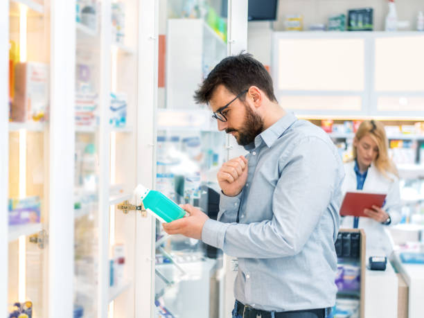 instructions de lecture d'homme sur la bouteille de pilule - pill bottle pharmacy medicine shelf photos et images de collection