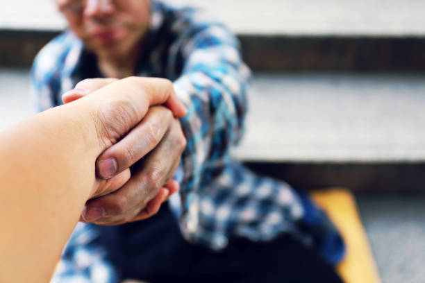 Close-up handshake for help homeless man on walking street in the capital city. stock photo
