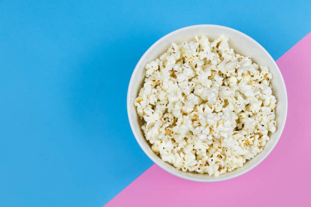 istock White bowl of popcorn on a bright pink and blue background with copy space. 1133602882