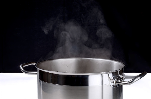 Stainless steel pot with boiling water and steam over it.