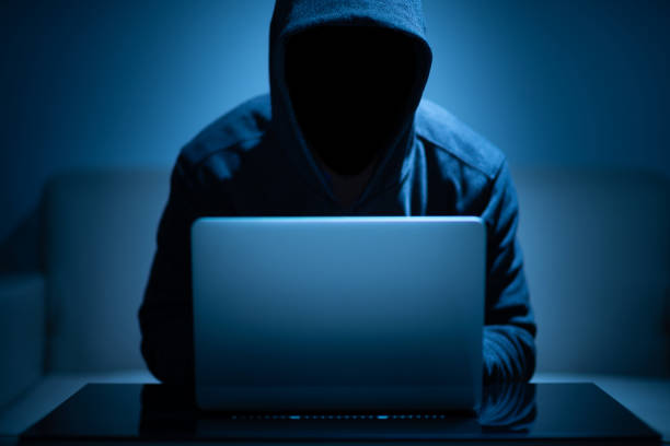 Hacker dark face using laptop stock photo