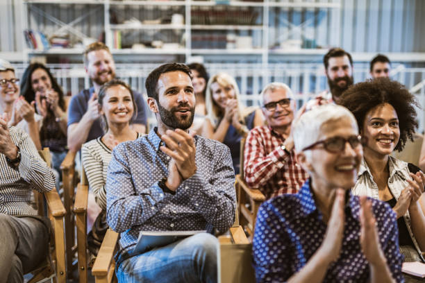 große gruppe von unternehmern applaudiert ihrem kollegen nach seminar in vorstandsetaar - applaudieren fotos stock-fotos und bilder