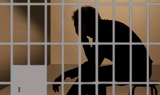 prisionero en la cárcel, silueta más allá de los bares photo