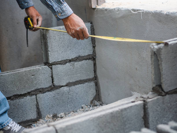 istock professional construction worker uses measuring Tape for measure and laying bricks with cement. 1133609059
